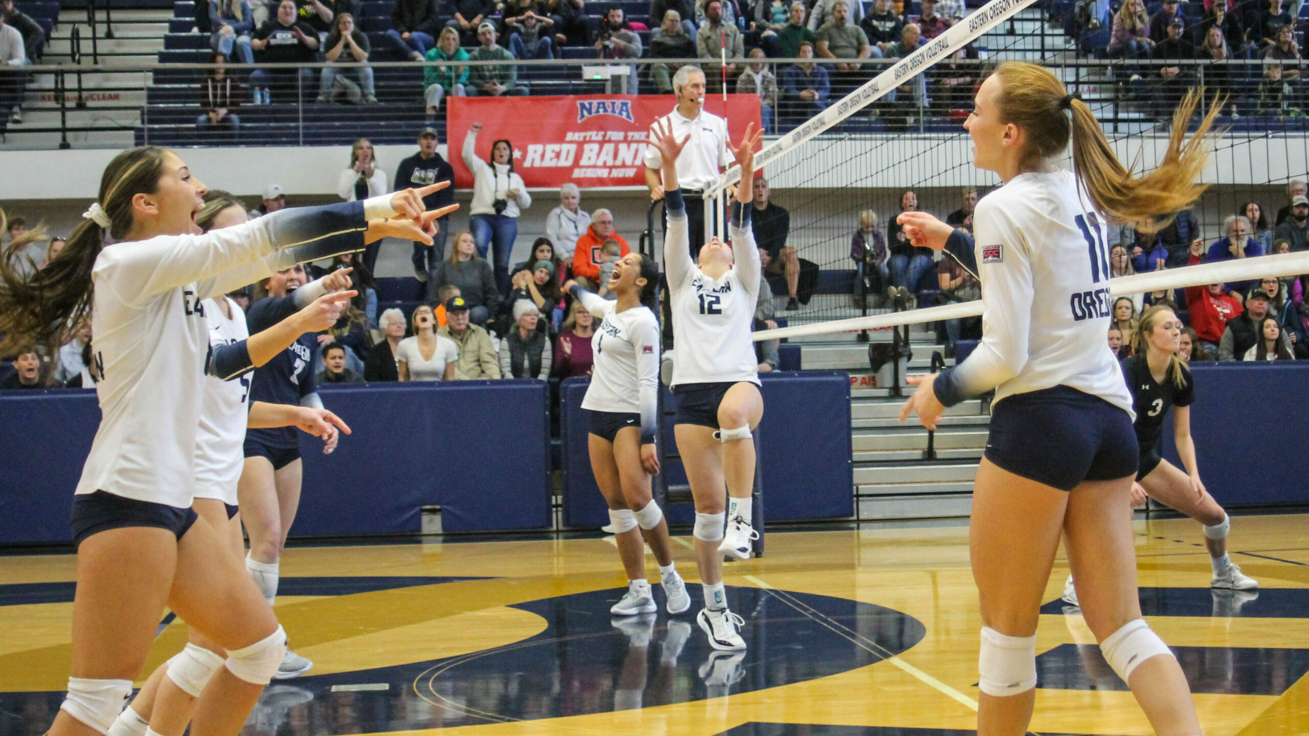 Eastern Oregon University Volleyball team celebrating winning a point