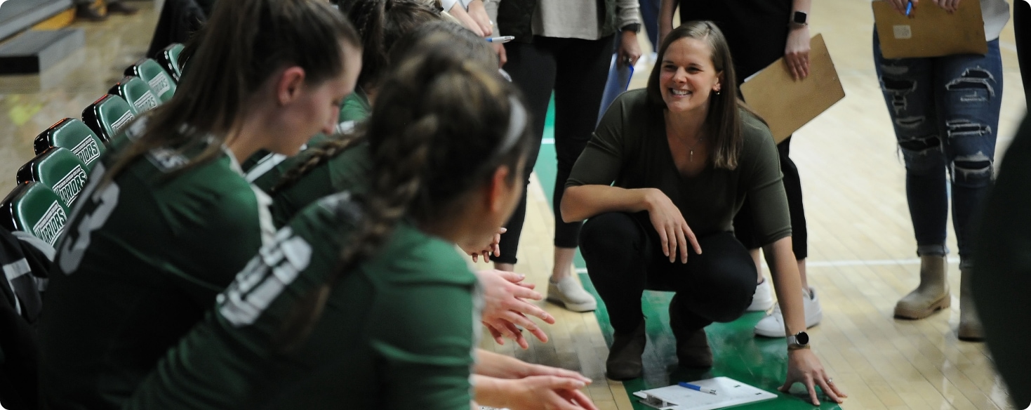 Volleyball coach with her team at the bench