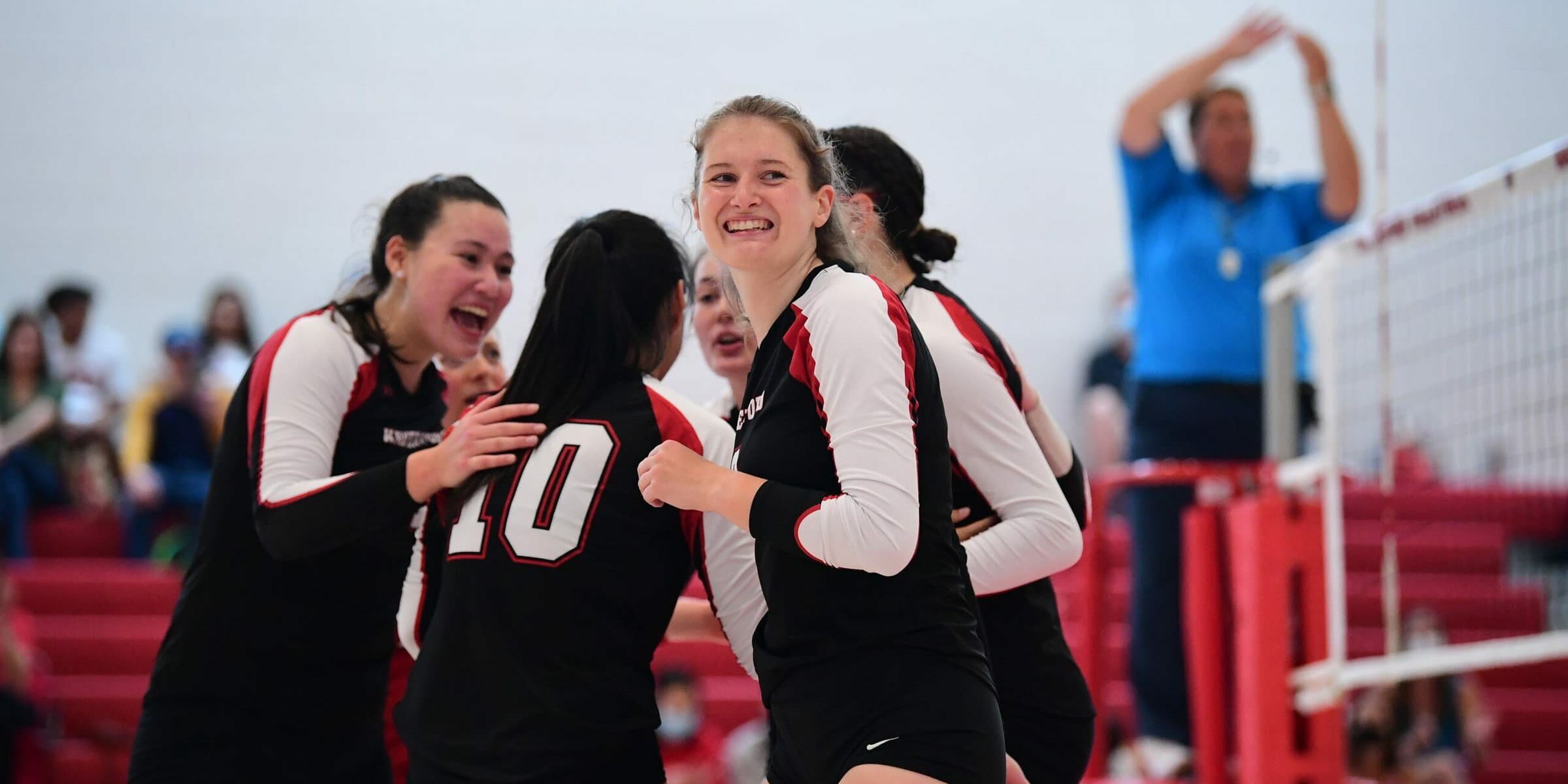 Volleyball huddle with athlete smiling to the sideline