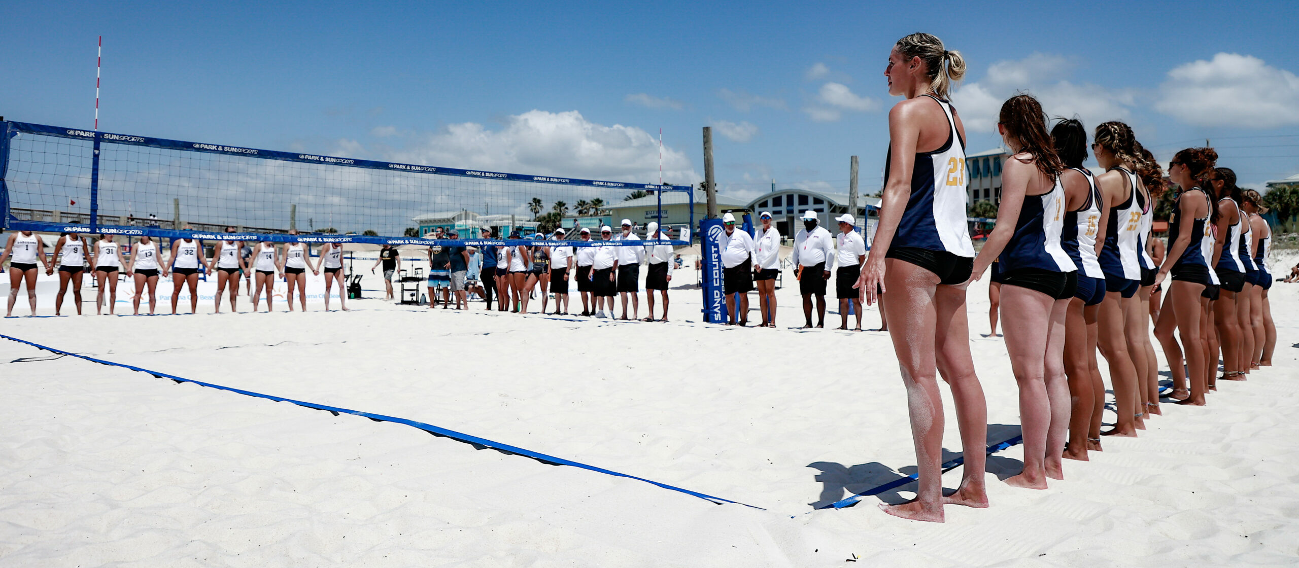 Two beach volleyball teams standing on the end line before a match