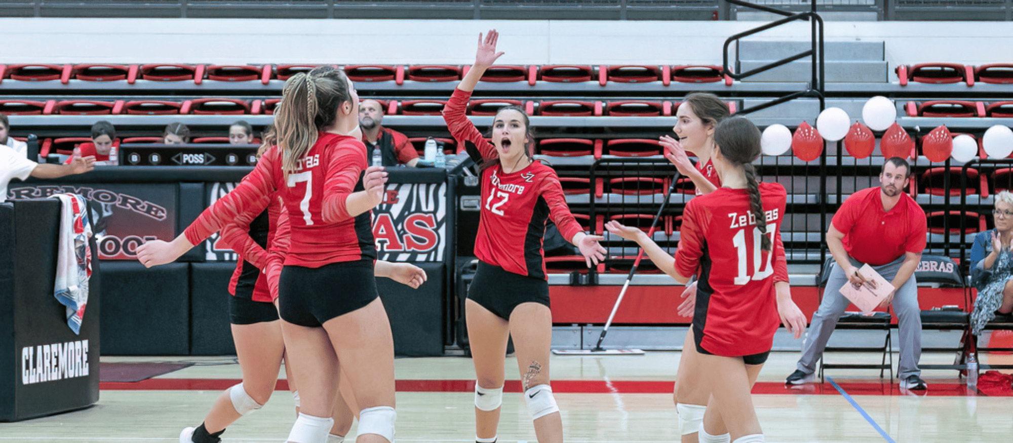Volleyball players celebrating in the middle of the court after scoring a point