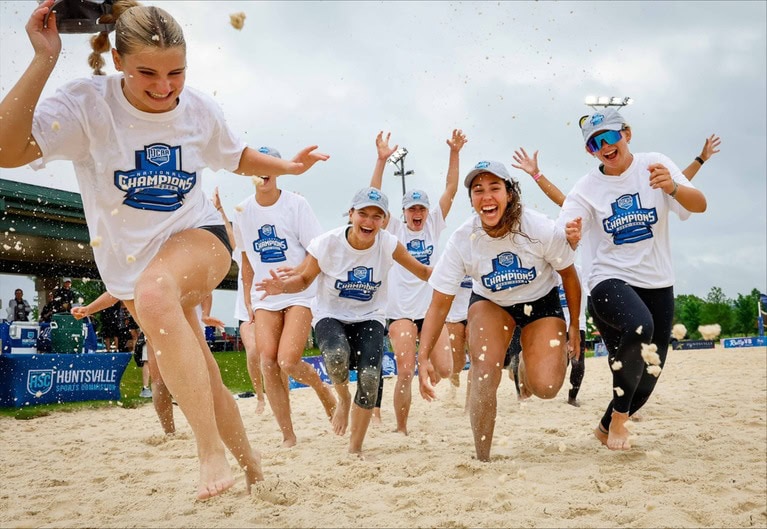 beach volleyball champions running through water