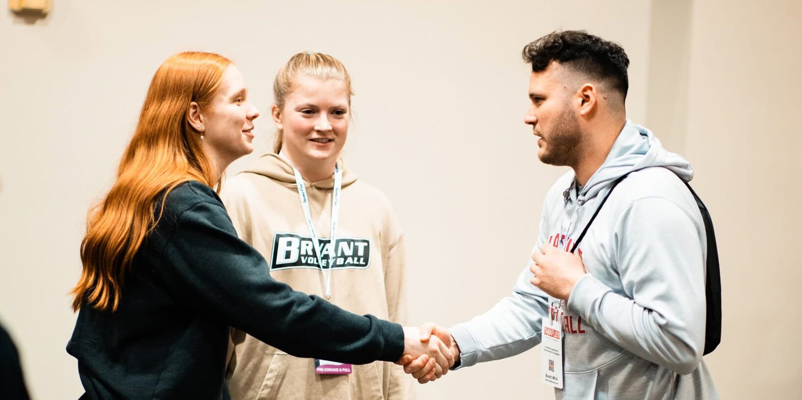 Three volleyball coaches talking and two of them are shaking hands