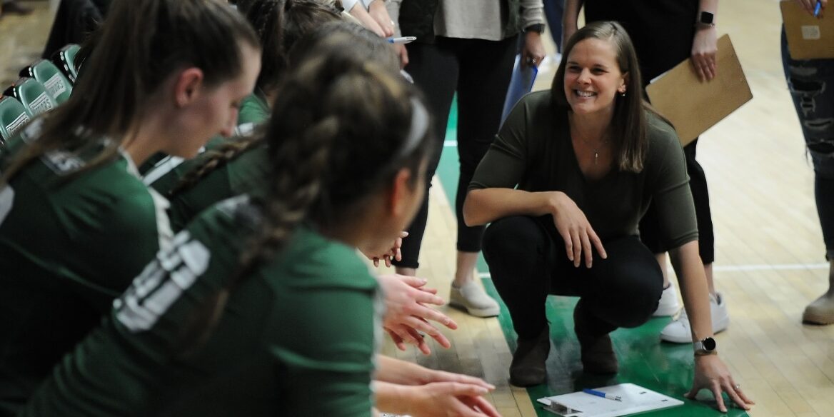 Volleyball coach with her team at the bench