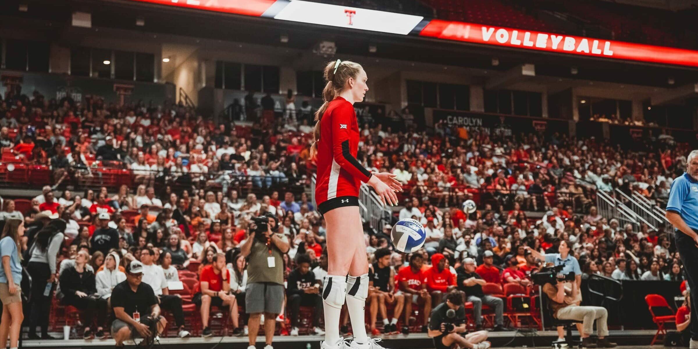 Texas Tech volleyball player getting ready to serve in front of a large crowd